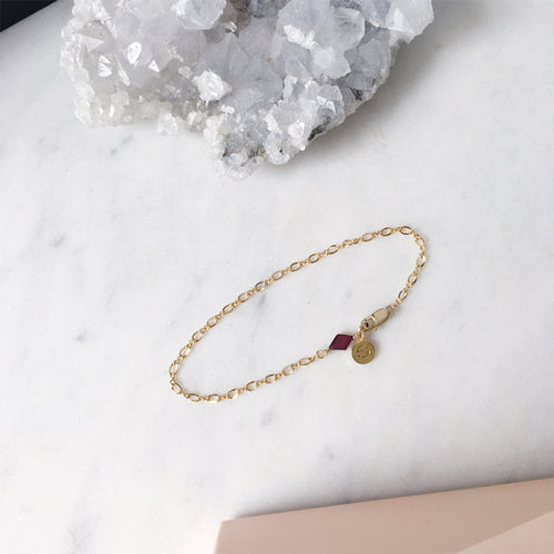 Fine gold bracelet with a red garnet gemstone charm